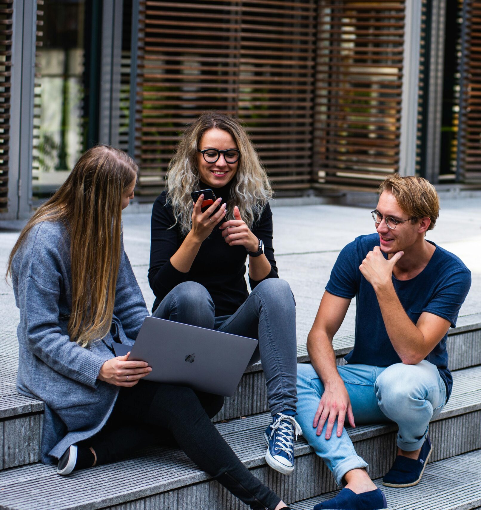 Three Persons Sitting on the Stairs Talking With Each Other